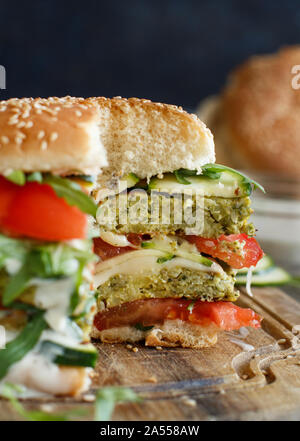 Un sano hamburger vegetariano con broccoli burger, rucola, zucchine e pomodori Foto Stock