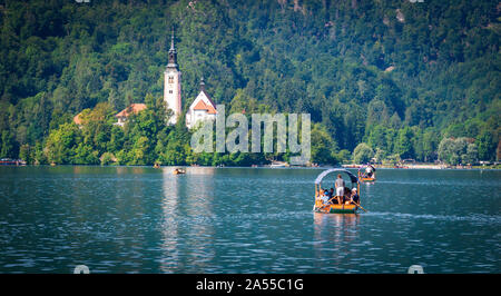 Tradizionali barche di legno sul lago di Bled con la Chiesa di Santa Maria Assunta sulla isola di Bled in Alta Carniola, Slovenia Foto Stock