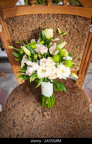 Anello e bouquet di fiori diversi su una sedia Foto Stock