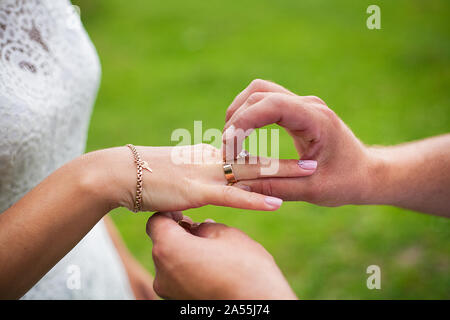 Lo sposo indossa l'anello sulla sposa la mano Foto Stock