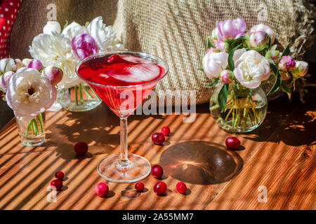 Rustico solenne ancora in vita con un bicchiere di rosso a bere con autunno bacche e ghiaccio circondati da fiori bianchi sul tavolo di legno nella diagonale ombra del Foto Stock