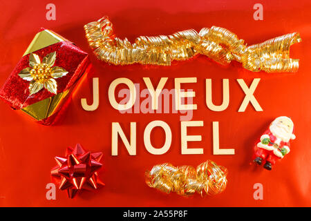 Buon Natale scritta in lingua francese con regali e decorazioni di Natale su sfondo rosso Foto Stock