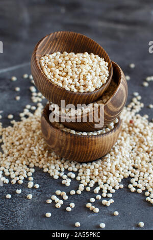 Bianco crudo grano di sorgo in ciotole su una tabella di colore grigio Foto Stock