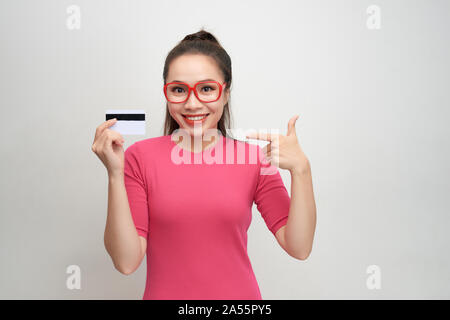 Foto di bella giovane donna isolato su sfondo bianco. Guardando la telecamera winking tenendo la carta di credito. Foto Stock