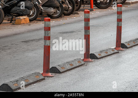 Barriera posti in plastica con pigmento riflettente su strada asfaltata. Vista giorno dell installato in arancione e bianco molla paracarri separazione di fronte al la Foto Stock