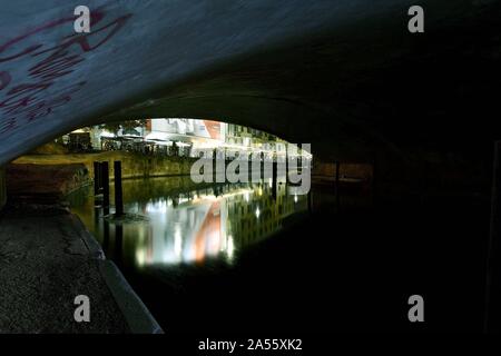 Ripresa orizzontale di splendidi edifici riflessi nel lago sotto un ponte di cemento a Milano Foto Stock