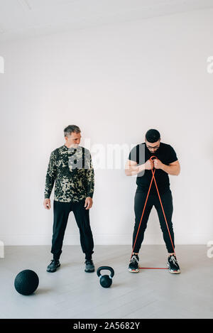 Istruttore di Fitness insegnamento uomo con banda di resistenza in studio Foto Stock