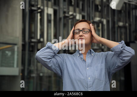 Ritratto di frustrazione e di sofferenza di mezza età della donna di affari con il mal di testa di emicrania dolore sensazione di esaurimento. Burnout. Foto Stock