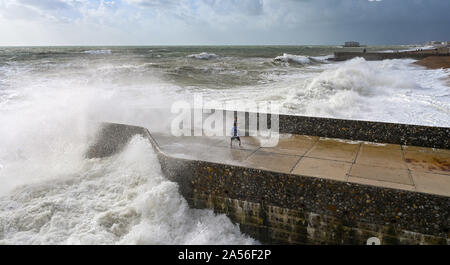 Brighton Regno Unito 18 ottobre 2019 - Visitatori coperti di sea spray come le onde in crash sul lungomare di Brighton come una miscela di venti forti rovesci di pioggia e sole sweep lungo la costa del sud come le perturbazioni atmosferiche continua in tutta la Gran Bretagna . Credito: Simon Dack / Alamy Live News Foto Stock