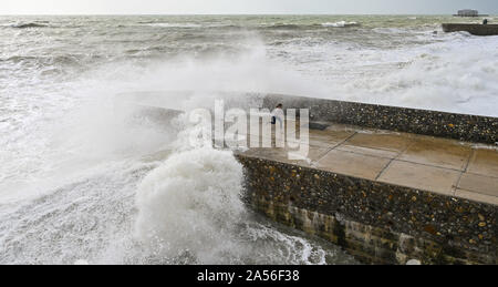 Brighton Regno Unito 18 ottobre 2019 - Visitatori coperti di sea spray come le onde in crash sul lungomare di Brighton come una miscela di venti forti rovesci di pioggia e sole sweep lungo la costa del sud come le perturbazioni atmosferiche continua in tutta la Gran Bretagna . Credito: Simon Dack / Alamy Live News Foto Stock