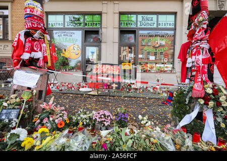 18 ottobre 2019, Sassonia-Anhalt, Halle: fiori, candele, ventola sciarpe e altri oggetti devozionali da HFC giacciono e appendere nella parte anteriore del Kiez-Döner. Il Ministro Presidente Haseloff e il governo federale il Commissario per le vittime hanno visitato il Kiez-Döner, che ha risentito di un estremista di destra attacco terroristico. Entrambi hanno assicurato il proprietario dello snack bar e i suoi collaboratori del loro supporto. Il 9 ottobre il tedesco Stephan B., pesantemente armati, aveva tentato prima di penetrare in una sinagoga. Quando il suo piano non riuscita ha girato un 40-anno-vecchia donna sulla strada e poco dopo un 20-anno-vecchio m Foto Stock