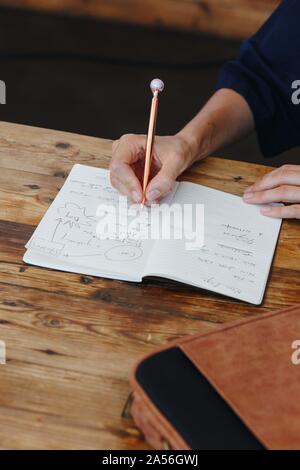 Donna iscritto in notebook sul piano del tavolo Foto Stock
