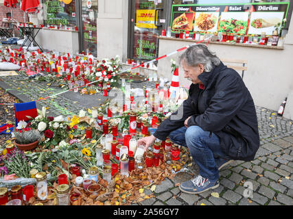 18 ottobre 2019, Sassonia-Anhalt, Halle: Andreas Splett, testimone oculare dell'attacco, Squat nella parte anteriore dei fiori e candele di fronte alla Kiez-Döner. Il Ministro Presidente Haseloff e il governo federale il Commissario per le vittime hanno visitato il Kiez-Döner, che ha risentito di un estremista di destra attacco terroristico. Entrambi hanno assicurato il proprietario dello snack bar e i suoi collaboratori del loro supporto. Il 9 ottobre il tedesco Stephan B., pesantemente armati, aveva tentato prima di penetrare in una sinagoga. Quando il suo piano non riuscita ha girato un 40-anno-vecchia donna sulla strada e poco dopo un 20-anno-vecchio Foto Stock