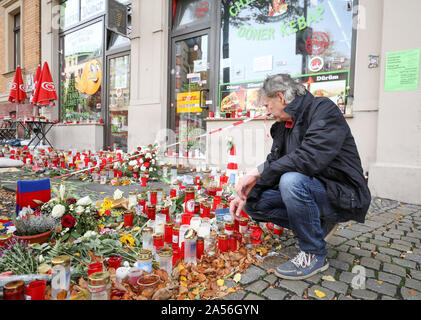 18 ottobre 2019, Sassonia-Anhalt, Halle: Andreas Splett, testimone oculare dell'attacco, Squat nella parte anteriore dei fiori e candele di fronte alla Kiez-Döner. Il Ministro Presidente Haseloff e il governo federale il Commissario per le vittime hanno visitato il Kiez-Döner, che ha risentito di un estremista di destra attacco terroristico. Entrambi hanno assicurato il proprietario dello snack bar e i suoi collaboratori del loro supporto. Il 9 ottobre il tedesco Stephan B., pesantemente armati, aveva tentato prima di penetrare in una sinagoga. Quando il suo piano non riuscita ha girato un 40-anno-vecchia donna sulla strada e poco dopo un 20-anno-vecchio Foto Stock