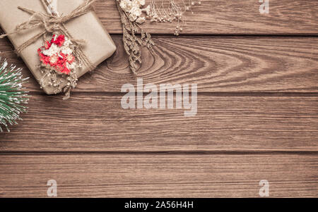 Realizzato a mano DIY scatola regalo su uno sfondo di legno. Presente naturale scatole per Natale e Capodanno o altro anniversario. Biglietto di auguri con copia spazio. Foto Stock