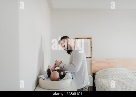 Giovane uomo modifica baby figlio il pannolino in camera da letto Foto Stock