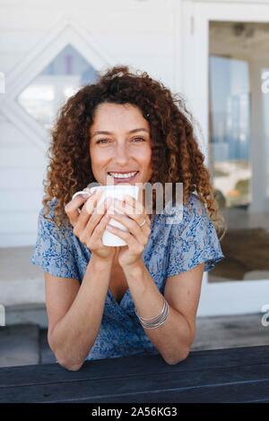 Donna gustando una bevanda calda giunte in mani a casa Foto Stock