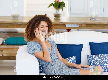 Donna che parla sul cellulare sul divano Foto Stock