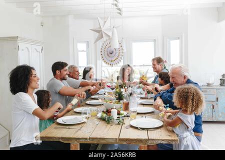 Famiglia popping Christmas Cracker insieme al tavolo da pranzo Foto Stock