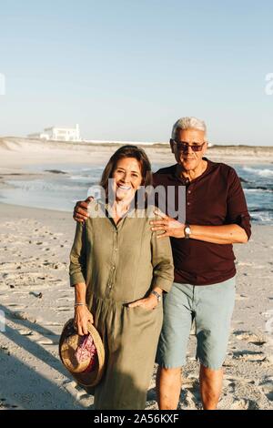 Coppia senior godendo di sole sulla spiaggia sabbiosa Foto Stock