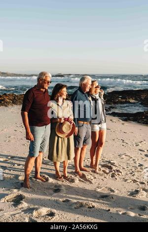 Coppie Senior godendo di sole sulla spiaggia sabbiosa Foto Stock