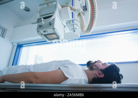 Giovane maschio paziente avente una scansione TC nel reparto di radiologia, vista laterale Foto Stock