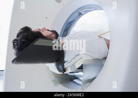 Giovane maschio paziente avente una scansione TC nel reparto di radiologia, basso angolo di visione Foto Stock