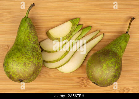 Gruppo di due interi cinque fette di fresco verde pera flatlay su legno chiaro Foto Stock