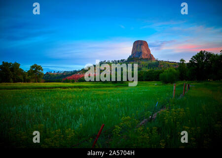 Sunrise a Devils Tower National Monument con wired recinzione in primo piano. Foto Stock