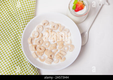 Deliziosi e nutrienti loop di cereali in una ciotola con il latte per la sana prima colazione per i bambini. Foto Stock