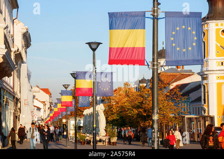 Linea di lanterne di strada con le bandiere della Unione europea e la Repubblica di Romania presso la Avenue Eroilor. Cluj-Napoca, Romania Foto Stock