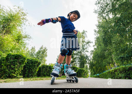 Active sport per bambini in età prescolare. Bambino su pattini a rotelle in linea nel parco. I ragazzi imparano a pattino lame a rullo. Bambina pattinaggio sulla soleggiata giornata estiva. Outdoor ac Foto Stock