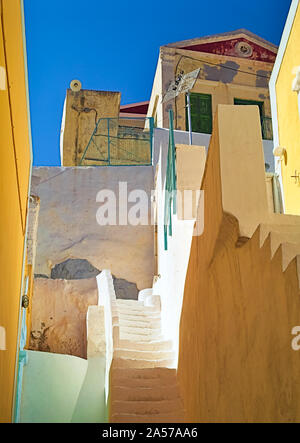 Scale tra le case di Symi Island, Grecia. Vernice gialla contrasta con il profondo blu del cielo. Foto Stock