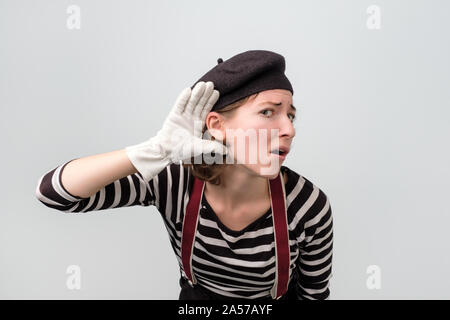 Giovani caucasici donna mime facendo un gesto dell'udito Foto Stock