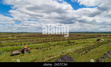 Il vecchio trattore rosso in un campo di essiccazione di torbiera, Irlanda rurale paesaggio Foto Stock