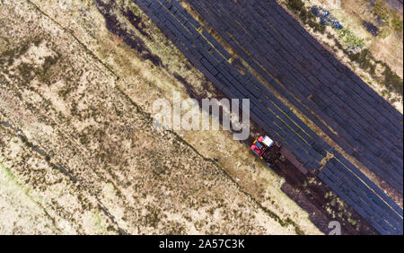 Vista aerea macchinari per la mietitura torbiera durante l inizio di estate in Irlanda rurale Foto Stock