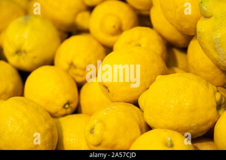 Pila di ripe il giallo dei limoni nel mercato estivo per la vendita, per lo sfondo Foto Stock