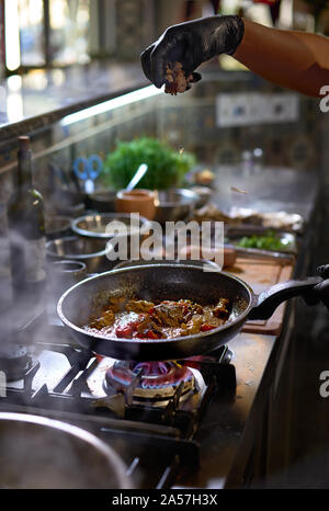 Concetto di cibo. Lo chef aggiunge tartufo friggere in una padella i pomodori e le ostriche. Il processo di cottura di spaghetti con frutti di mare. Foto Stock