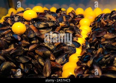 Pronto a mangiare le cozze farcite con il piccante riso cotto e limone. Street fast food concept. La regione mediterranea. Focuse selettiva. Foto Stock