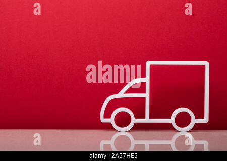 Close-up di una consegna simbolo carrello appoggiato sulla parete rossa Foto Stock