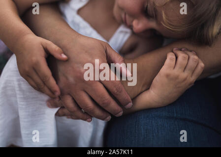 Sleeping ragazza giovane avvolto in sua madre di braccia Foto Stock