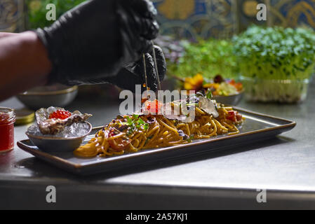 Concetto di cibo. Lo chef contorni con caviale rosso un pesce piatto di spaghetti. Messa a fuoco selettiva. Profondità di campo. Foto Stock