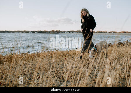 Donna che cammina il suo cane sulla spiaggia in inverno Foto Stock