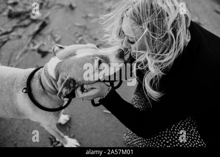Donna baciare il suo cane sulla spiaggia Foto Stock