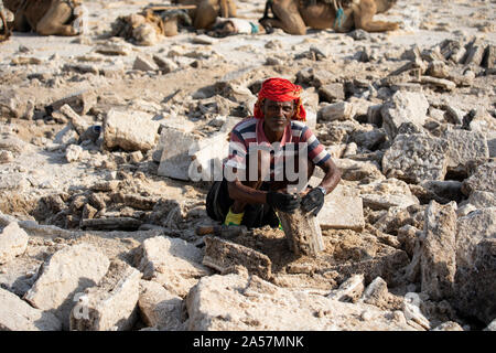 Un uomo dal lontano gruppo etnico lavora sulla pianura di sale nella depressione di Danakil, Etiopia. Foto Stock