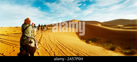 I turisti a cavallo di cammelli attraverso il deserto del Sahara paesaggio, Marocco Foto Stock