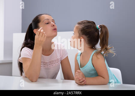 Un attraente femmina Logopedista aiuta la ragazza come pronunciare i suoni in Office Foto Stock