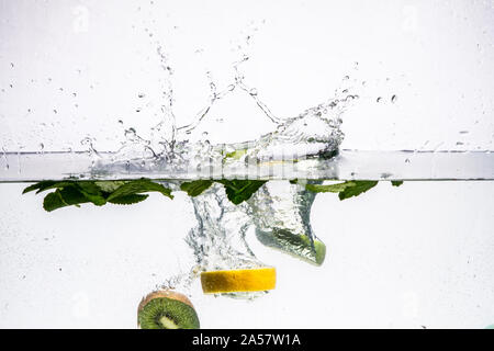 Un background di formazione di bolle in acqua blu dopo la frutta viene fatta cadere in esso. Foto Stock