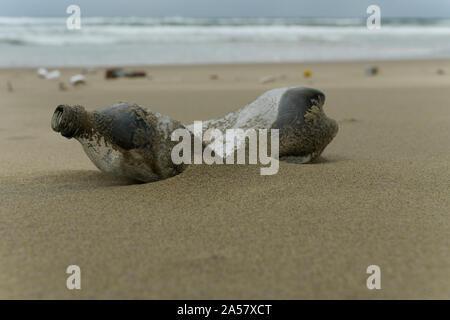 Inquinamento di plastica, bottiglia di PET in sabbia, contenitore monouso lavato fino sulla spiaggia, imballaggi alimentari, close up, oggetto, in situ, Durban, Sud Africa Foto Stock