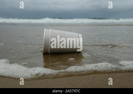 Durban, Sud Africa, mare di acqua di lavaggio bicchiere monouso sulla spiaggia, inquinamento, estrarre, uso singola, vicino il littering in situ Foto Stock